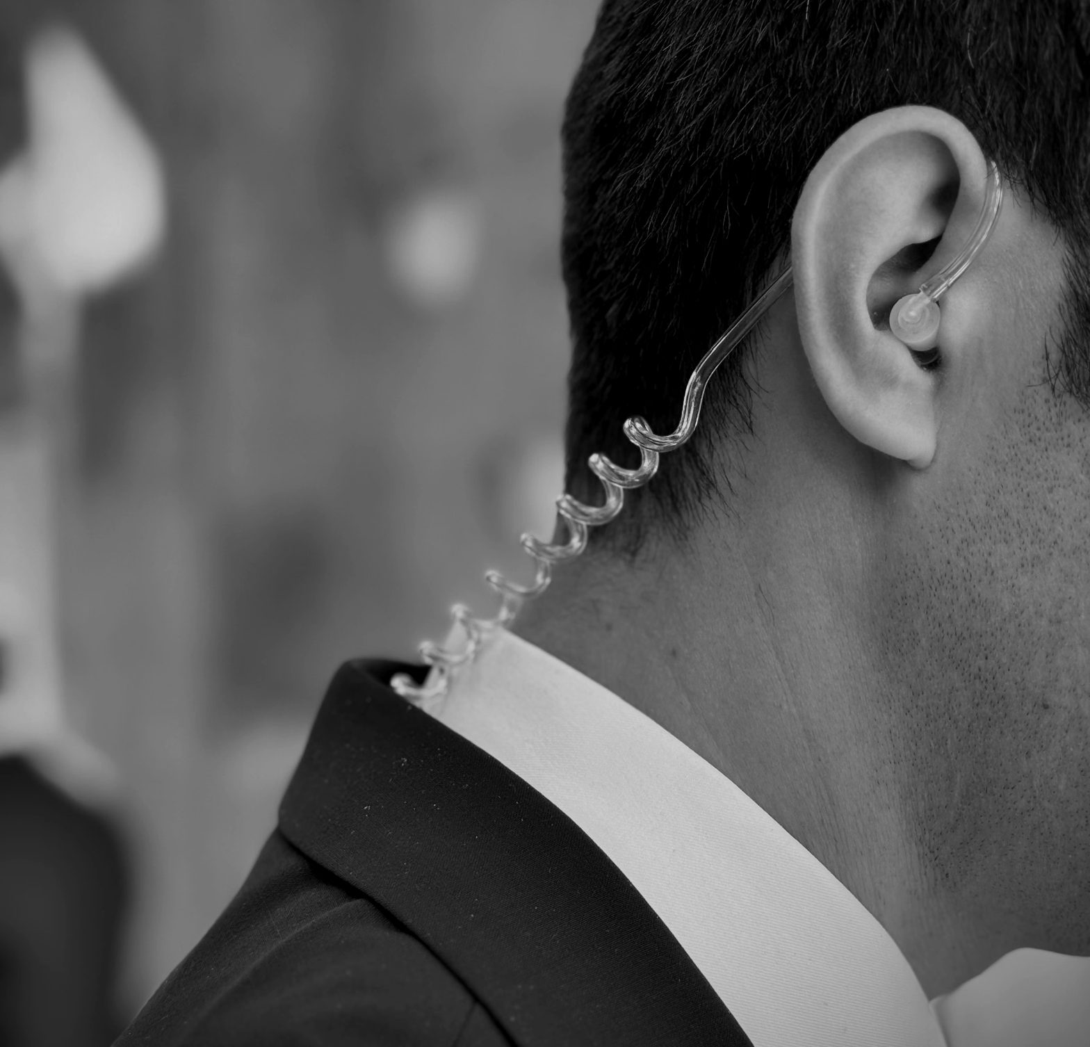 Close-up of a bodyguard in a suit wearing a coiled security earpiece