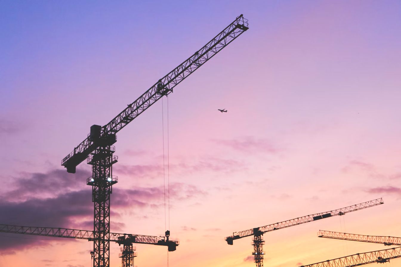 Tower cranes at dusk over a development site